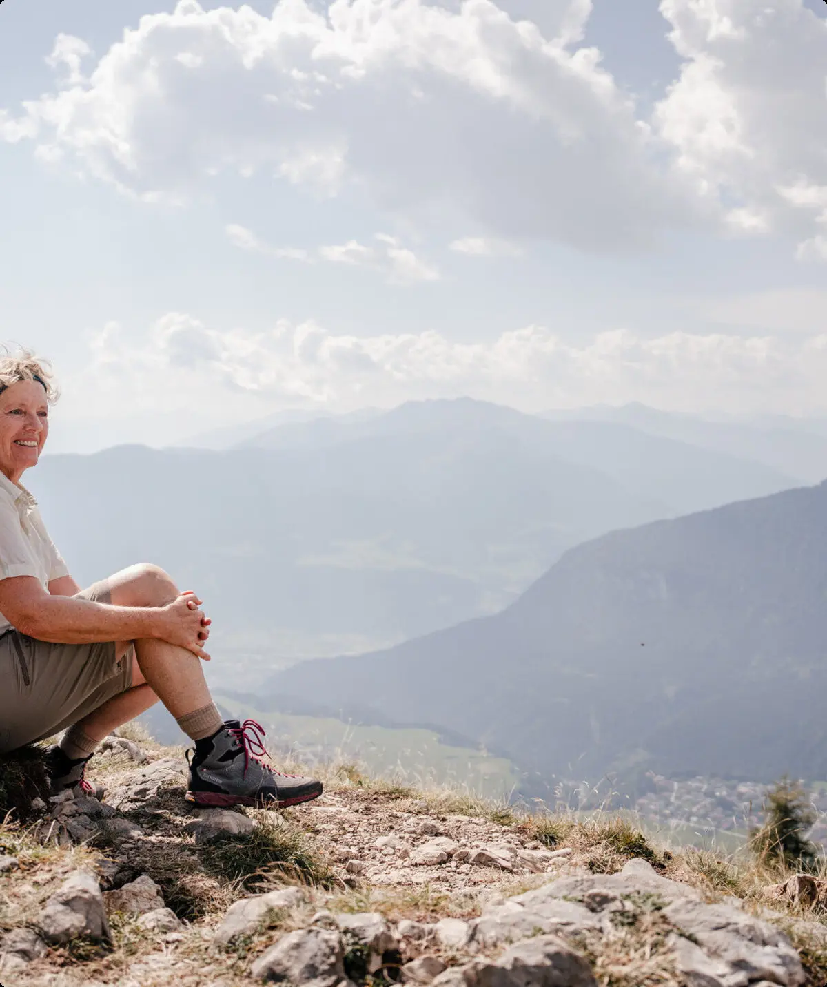 Eine ältere Dame sitzt zufrieden auf einem Felsplateau | © DAV / Marisa Koch